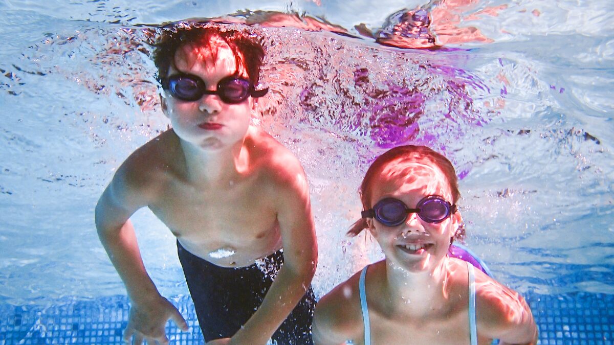 水中にもぐってこちらに笑顔を向ける小学生の男女